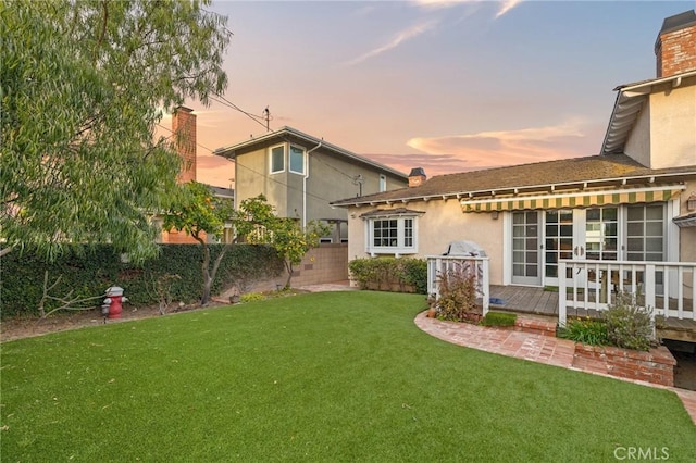 view of yard with french doors, fence, and a wooden deck