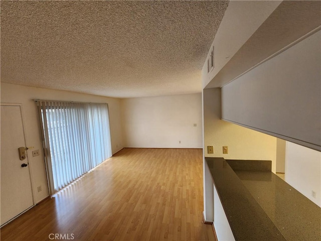 unfurnished living room with a textured ceiling and wood finished floors