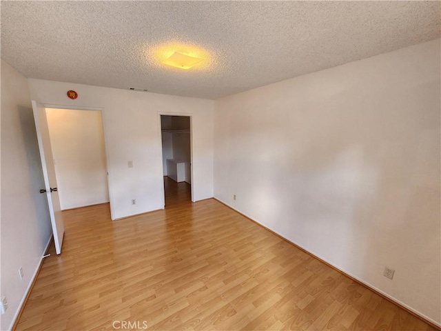 unfurnished bedroom featuring a closet, a textured ceiling, and light wood finished floors