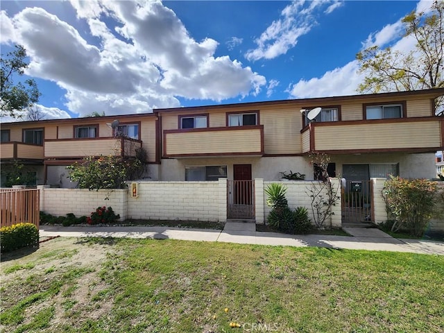 multi unit property with a front yard, a fenced front yard, a gate, and stucco siding