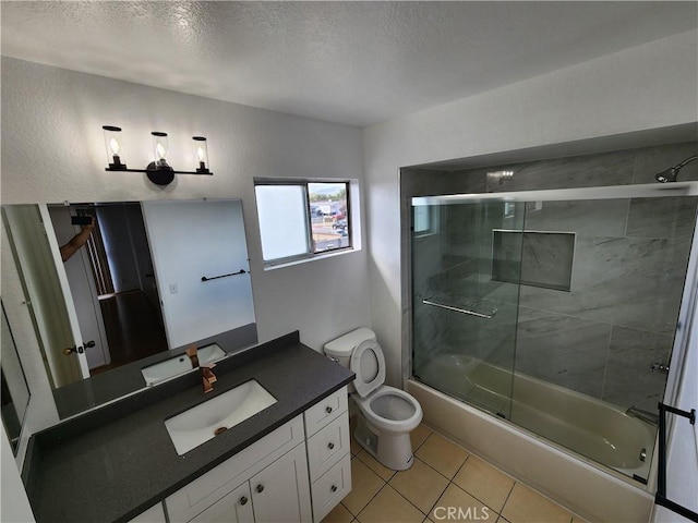 full bath featuring toilet, tile patterned flooring, combined bath / shower with glass door, a textured ceiling, and vanity