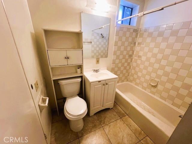 bathroom featuring washtub / shower combination, toilet, vanity, and tile patterned flooring