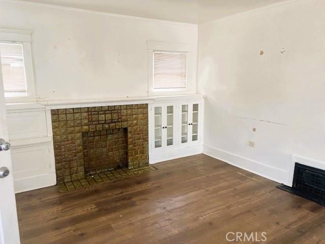 unfurnished living room with ornamental molding, wood finished floors, baseboards, and a tile fireplace