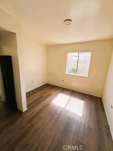 empty room featuring baseboards and dark wood-style flooring