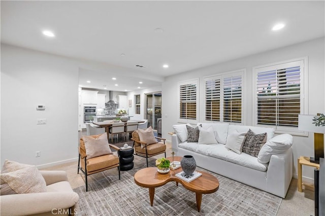 living room with recessed lighting, visible vents, light carpet, and baseboards