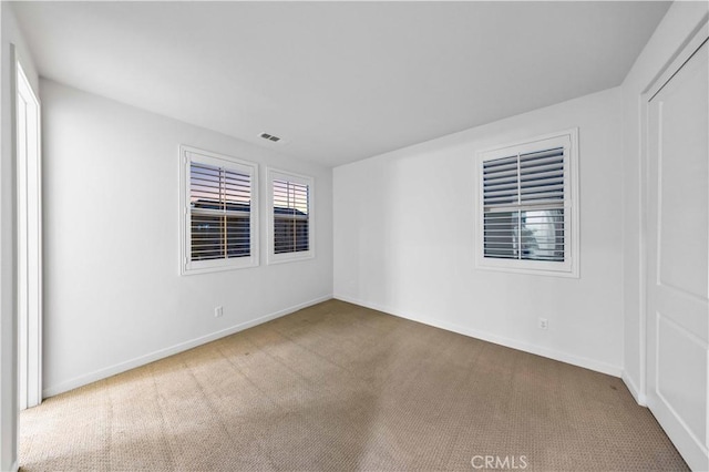 empty room featuring carpet, visible vents, and baseboards