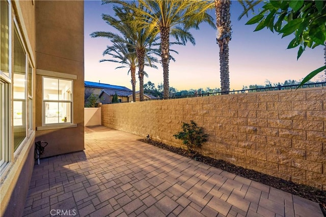 patio terrace at dusk featuring a fenced backyard