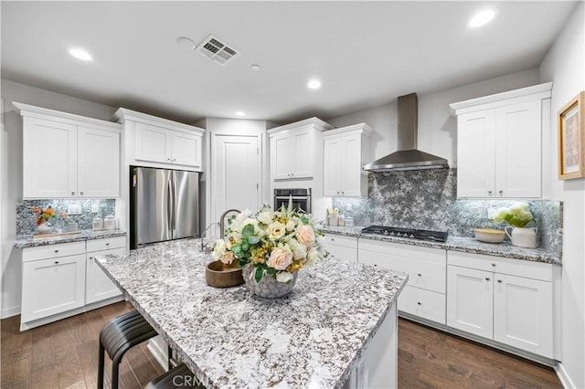 kitchen with wall chimney range hood, appliances with stainless steel finishes, and white cabinetry