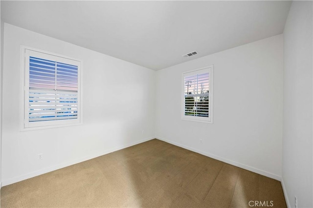 carpeted empty room with visible vents and baseboards