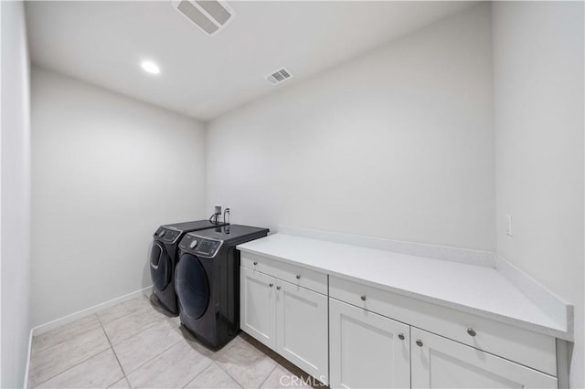 clothes washing area featuring cabinet space, light tile patterned flooring, visible vents, and independent washer and dryer