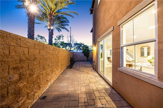 property exterior at dusk with a fenced backyard, a patio, and stucco siding