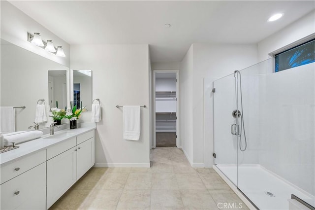 full bath with baseboards, tile patterned flooring, a spacious closet, vanity, and a shower stall