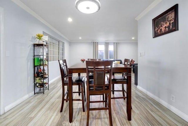 dining room featuring light wood finished floors, baseboards, crown molding, and recessed lighting