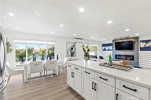 kitchen featuring light wood-type flooring, a large fireplace, recessed lighting, and a wall mounted AC