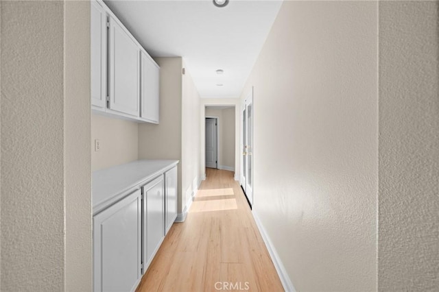 hallway with light wood-style flooring and baseboards