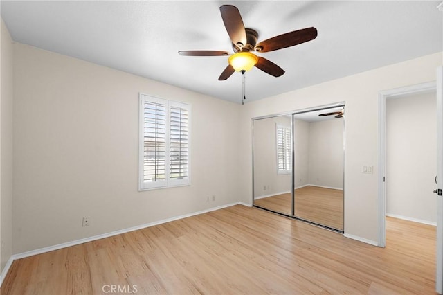 unfurnished bedroom featuring a ceiling fan, a closet, light wood-style flooring, and baseboards