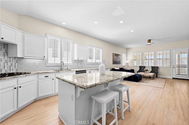 kitchen featuring black gas cooktop, backsplash, a sink, and a kitchen island