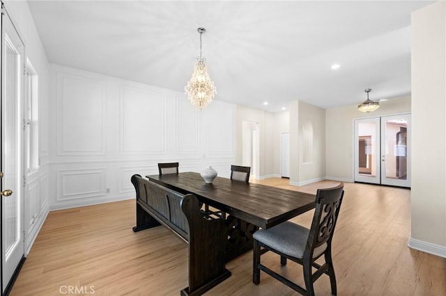 dining area with a chandelier, light wood-style flooring, recessed lighting, a decorative wall, and baseboards