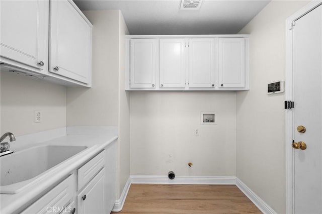 clothes washing area featuring washer hookup, light wood finished floors, cabinet space, visible vents, and a sink