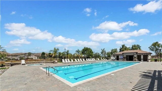 community pool featuring a community hot tub, a patio area, and fence