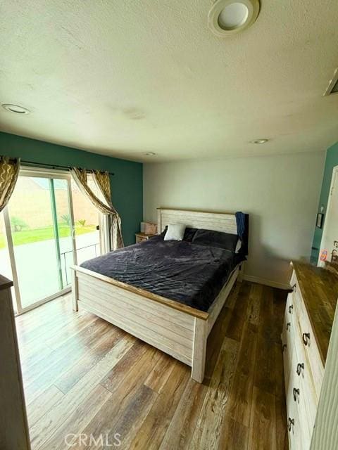 bedroom with access to outside, a textured ceiling, and wood finished floors