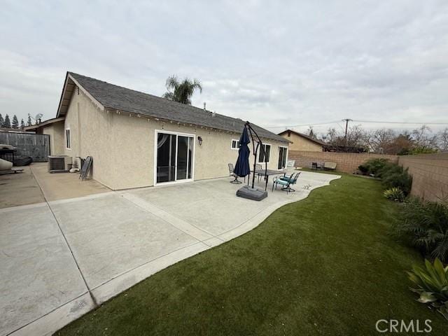 back of house with a lawn, a fenced backyard, a patio area, central AC, and stucco siding