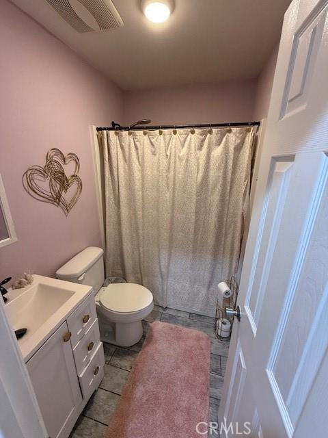 bathroom with visible vents, a shower with shower curtain, toilet, vanity, and tile patterned floors