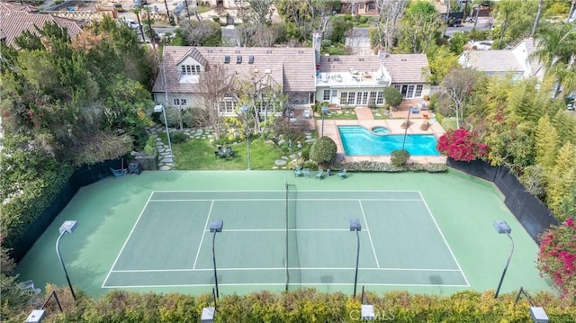 view of tennis court with a patio area, fence, and a pool with connected hot tub