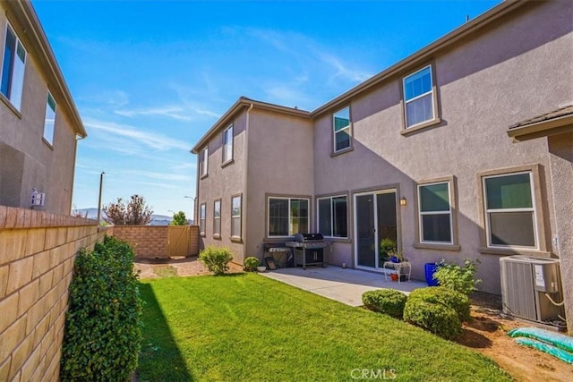 rear view of property with stucco siding, a lawn, a patio area, central AC, and a fenced backyard