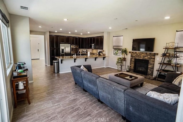 living room with a wealth of natural light, a fireplace, visible vents, and recessed lighting