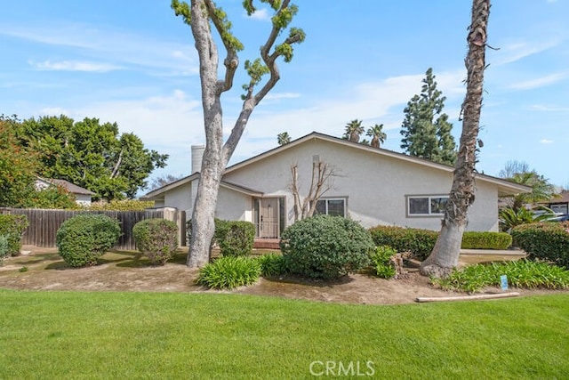 exterior space featuring stucco siding, a front lawn, and fence