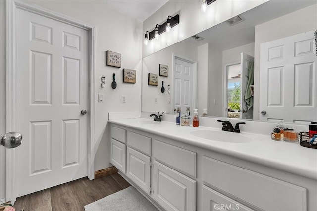 bathroom featuring visible vents, a sink, and wood finished floors