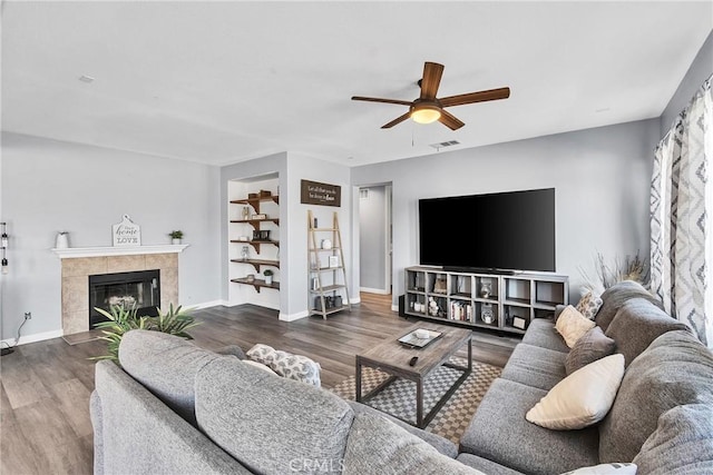 living area featuring a fireplace, visible vents, ceiling fan, wood finished floors, and baseboards