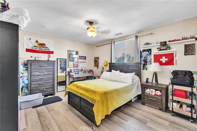 bedroom featuring a textured ceiling, ceiling fan, wood finished floors, and visible vents