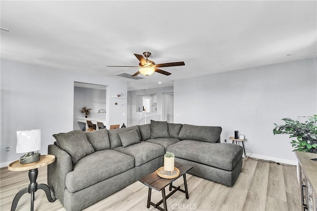 living area featuring baseboards, visible vents, ceiling fan, and light wood finished floors