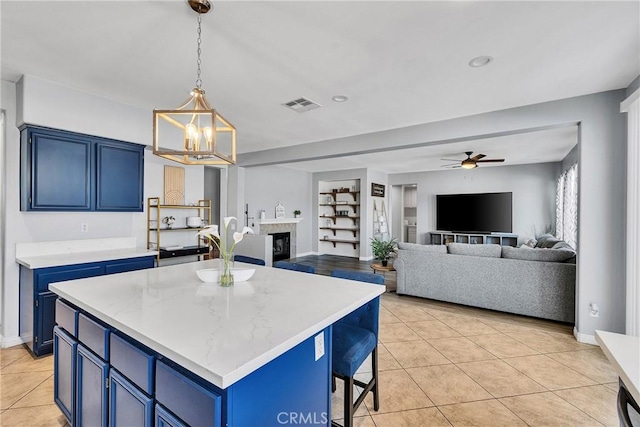 kitchen featuring blue cabinetry, light tile patterned flooring, a fireplace, and visible vents