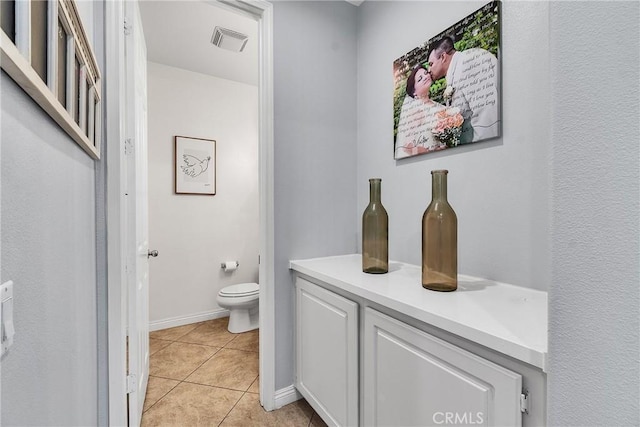 bathroom with toilet, tile patterned flooring, visible vents, and baseboards