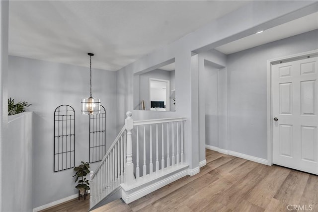 hallway featuring wood finished floors, an upstairs landing, and baseboards