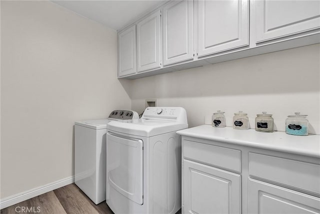 clothes washing area with cabinet space, independent washer and dryer, baseboards, and wood finished floors