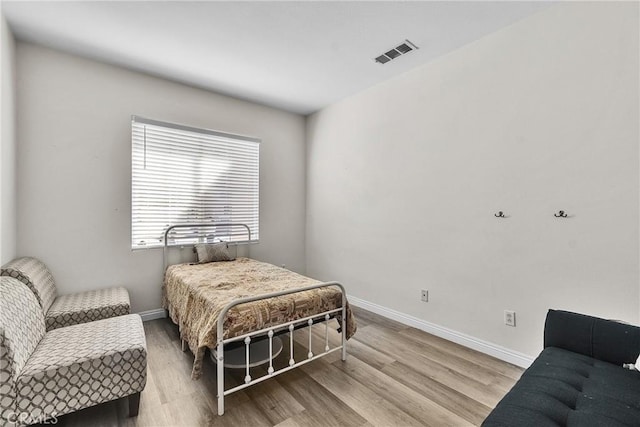 bedroom with visible vents, baseboards, and wood finished floors