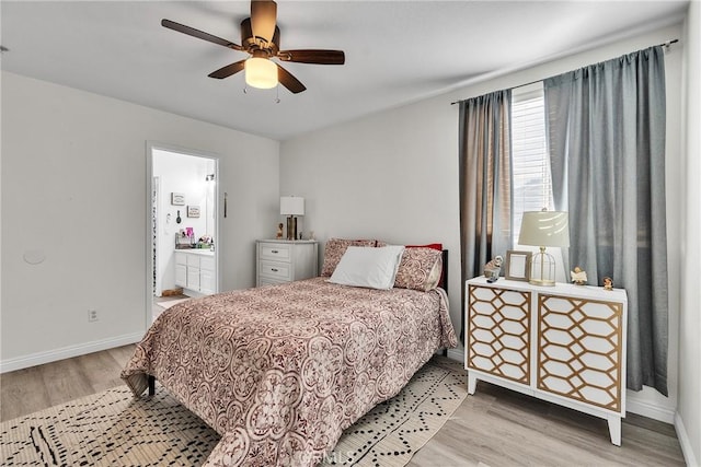 bedroom featuring ensuite bathroom, a ceiling fan, light wood-style flooring, and baseboards