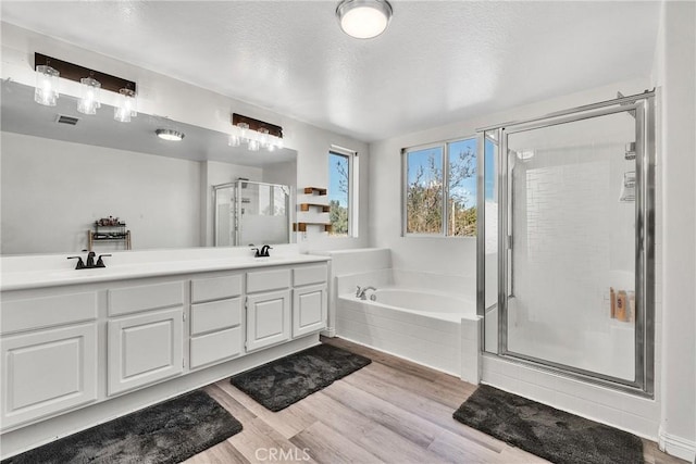 full bathroom featuring wood finished floors, a sink, visible vents, a bath, and a stall shower