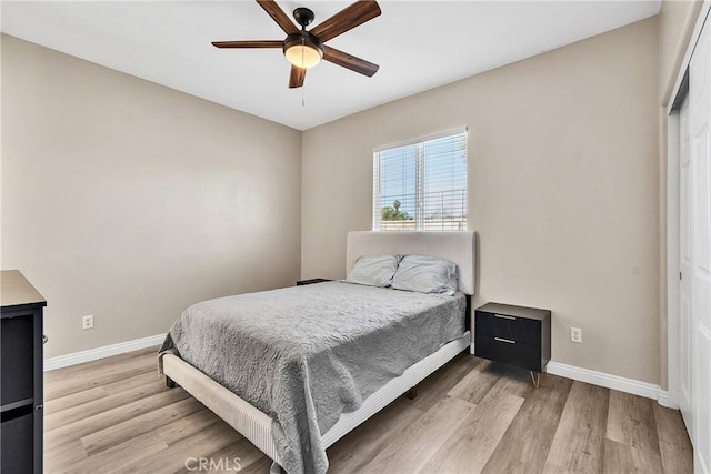 bedroom with light wood-style flooring, baseboards, and a ceiling fan