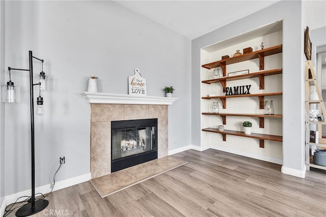 unfurnished living room featuring a fireplace, baseboards, and wood finished floors