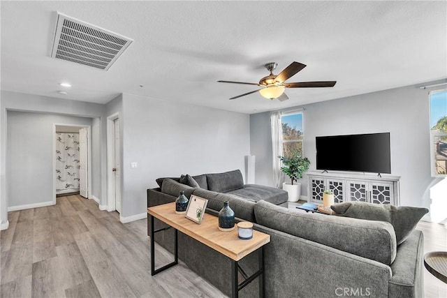 living area featuring light wood-type flooring, baseboards, visible vents, and a wealth of natural light