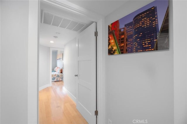 hall featuring visible vents, baseboards, and wood finished floors