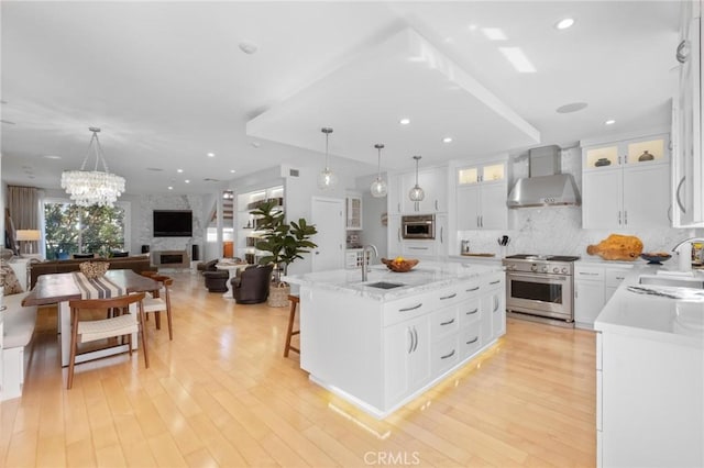 kitchen with high end range, wall chimney range hood, a large fireplace, and a sink