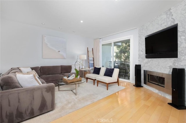 living area with recessed lighting, light wood-style flooring, and a high end fireplace