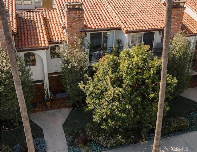 view of home's exterior with stucco siding, a tiled roof, and a chimney