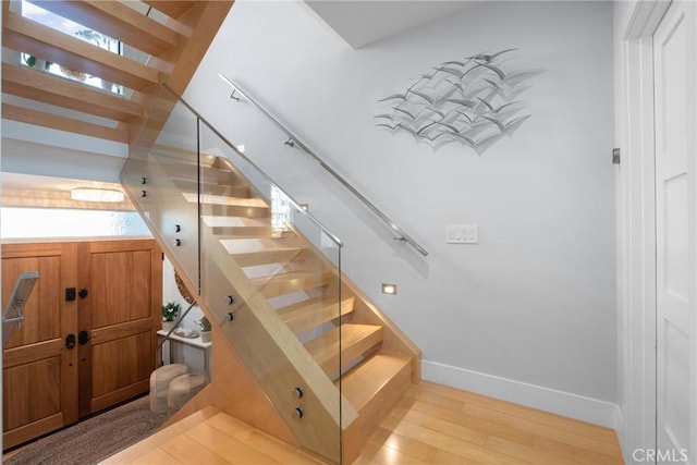 stairway featuring a wealth of natural light, baseboards, and wood finished floors